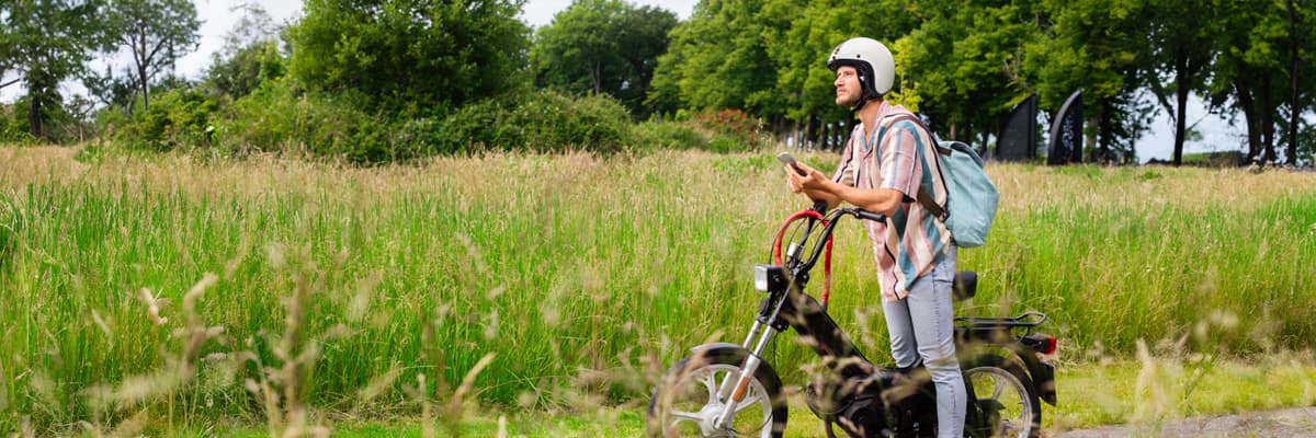 Man staat bij bromfiets te navigeren