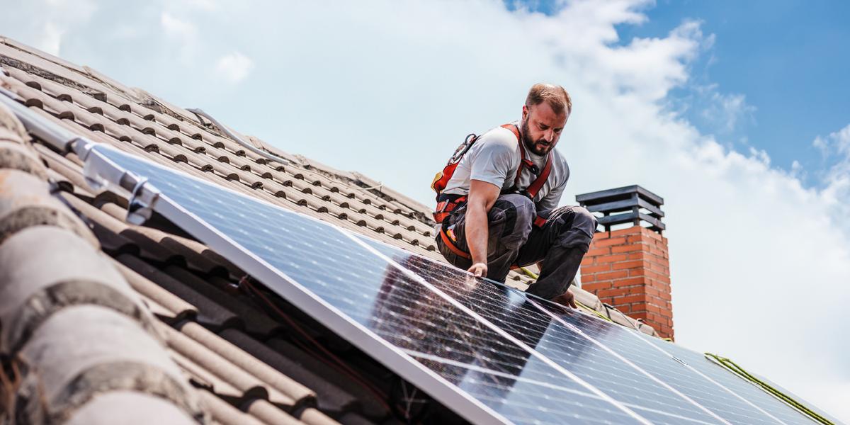 Man installeert duurzame zonnepanelen op het dak