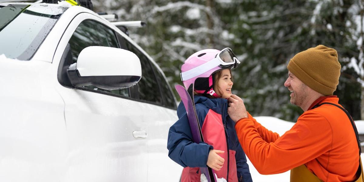 Man en kind met de auto op wintersportvakantie
