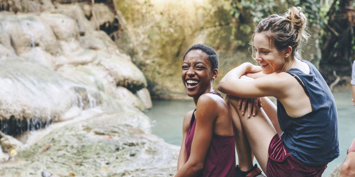 Twee lachende vrouwen bij een waterval tijdens hun reis in Suriname