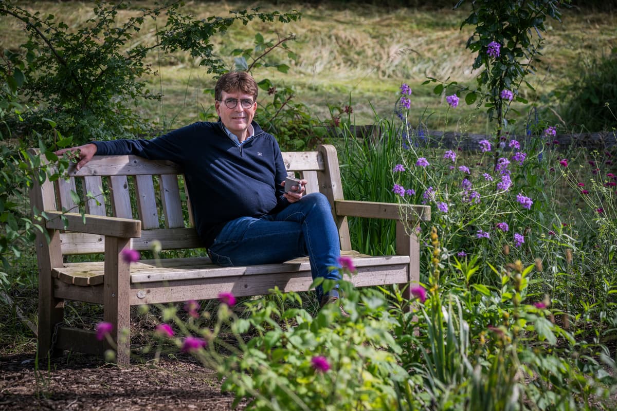 Buurtfonds manager Pieter van den Ban zit op een bankje in de natuur met een kop koffie in zijn hand